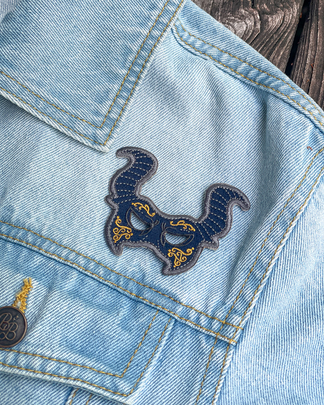 Shades of Magic patch for VE Schwab fans featuring a blue and gold masquerade mask.