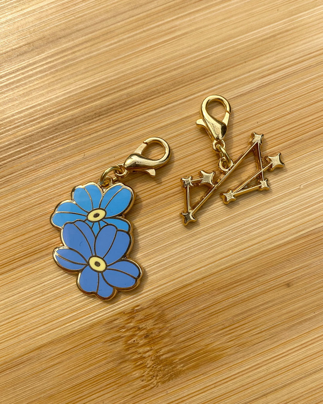 Addie LaRue charms featuring two forget me nots and a seven pointed constellation.