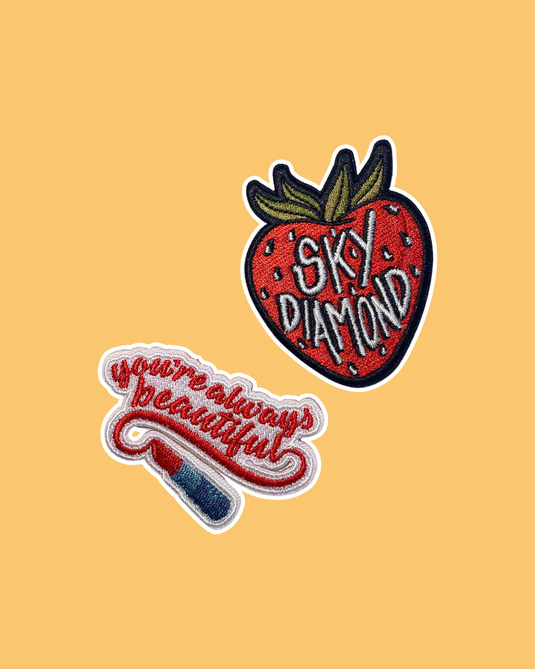 The Hating Game patches for Sally Thorne fans featuring a strawberry patch with the phrase 'Sky Diamond' written on it and a quote patch saying 'you're always beautiful' with an illustrated uncapped lipstick tube.