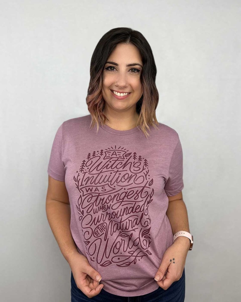 Wild is the Witch tee featuring the quote 'A witch's intuition was strongest when surrounded by the natural world' on an orchid shirt.