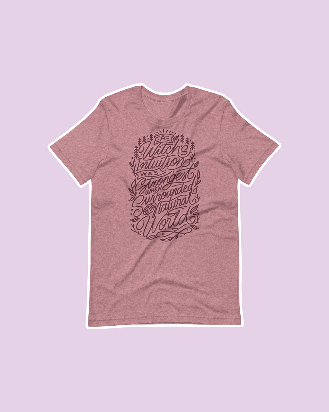 Wild is the Witch shirt featuring a orchid shirt featuring the quote 'A witch's intuition was strongest when surrounded by the natural world' in fun text effects and surrounded by pine trees and leaves. 