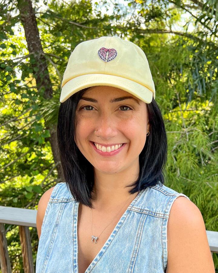 Fantasy cap in light yellow with a patch with angel wings on it.
