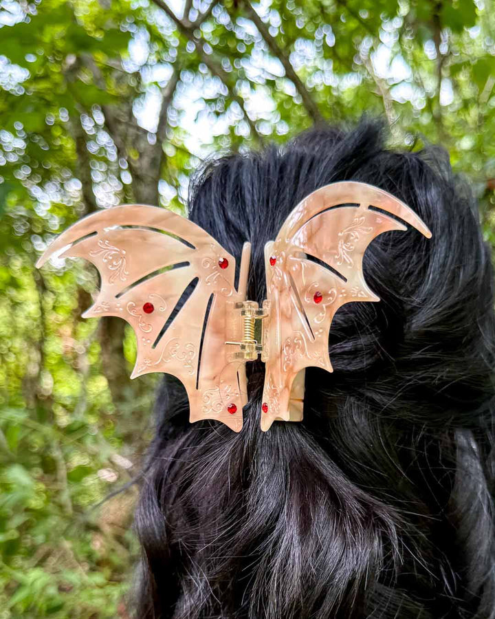 A dual-tone hair clip in pastel red with red gem embellishments inspired by the bat boys from A Court of Thorns and Roses by Sarah J. Maas. 