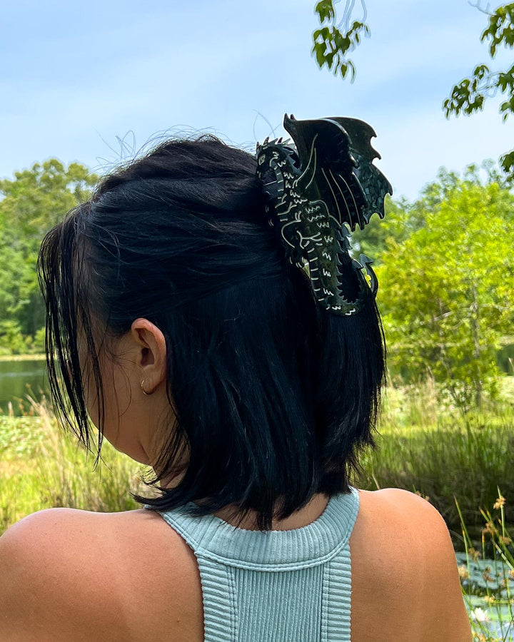 Hair clipped half-up-half-down with a black and silver detailed bookish hair clip for fantasy readers in the shape of a dragon.