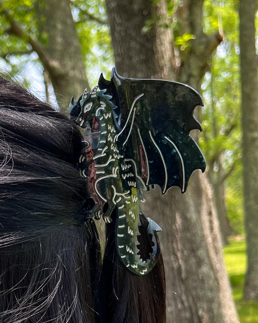 Bookish hair accessory in the shape of a dragon with black tones and silver etching details for fantasy readers.