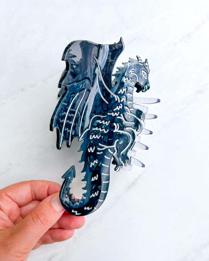 Fantasy reader hair clip with black and silver detailing in the shape of a dragon with its wings spread.