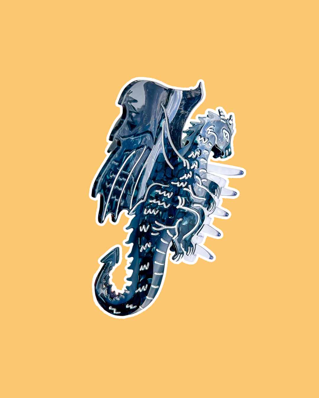 A fantasy hair claw clip with black tones and silver etching details in the shape of a dragon.
