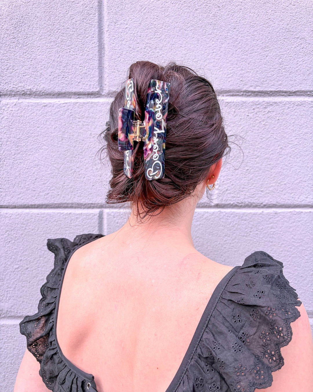 Woman in black wearing a claw clip for book fans featuring a dark, multi-colored design with the phrase "book lover" etched in white.