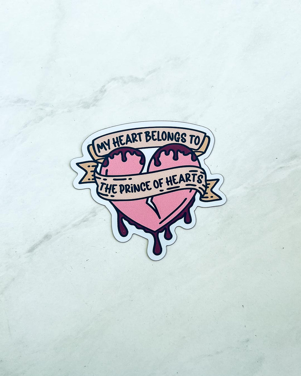 Illustrated matte magnet for Once Upon a Broken Heart fans featuring a broken, pink heart covered in blood and a banner with the phrase 'My heart belongs to the Prince of Hearts' on it.