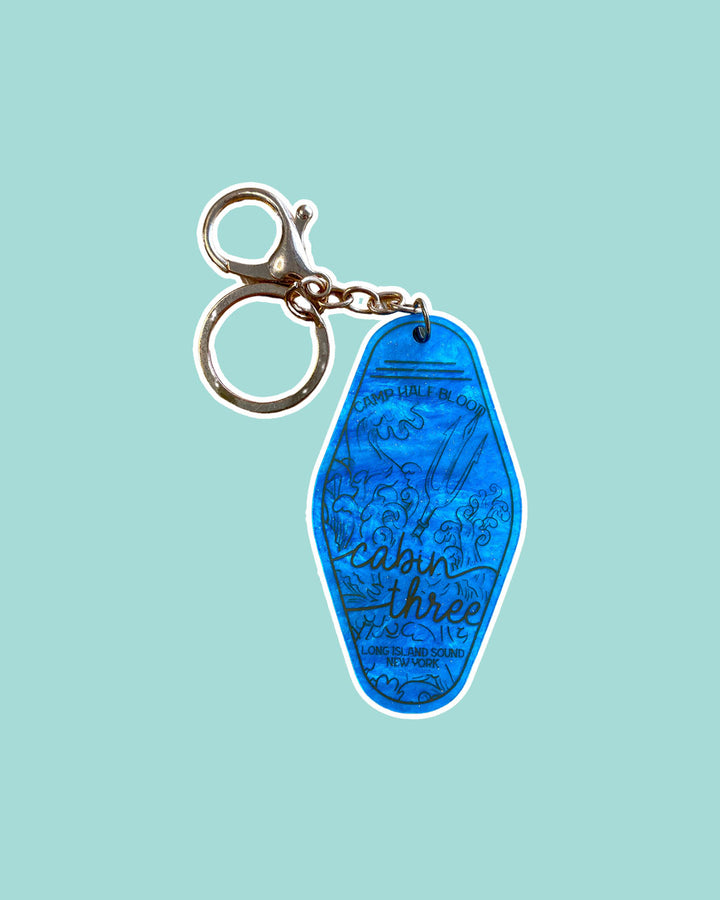 PJO keychain featuring a design for a motel key for Cabin Three, including illustrated waves and a trident. 