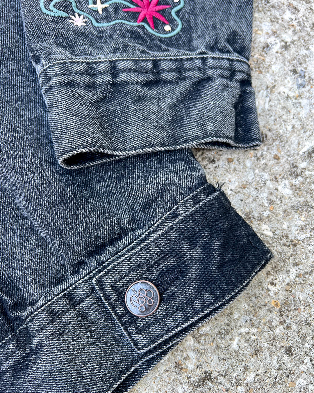 Close up of the Blissfully Bookish buttons on the embroidered jean jacket for fantasy fans.