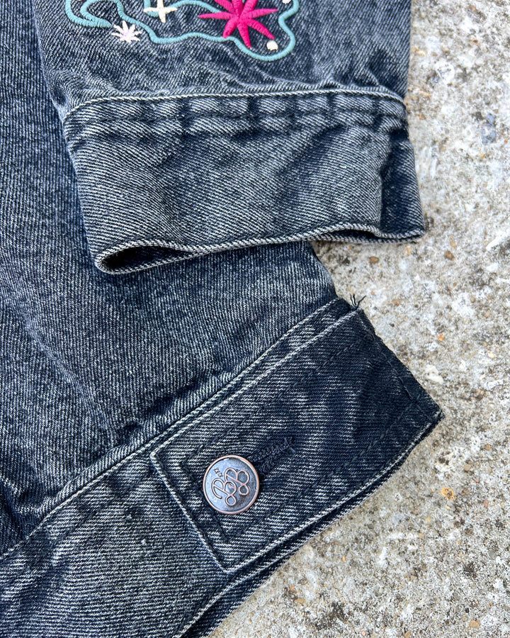 Close up of the Blissfully Bookish buttons on the embroidered jean jacket for fantasy fans.