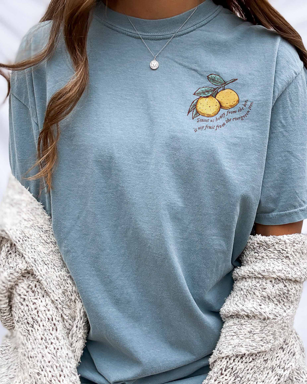 Kate Golden shirt for If Not For My Baby fans featuring two illustrated clementines on the left chest with the quote 'Sweet as honey from the bee, is my fruit from the evergreen tree' beneath it.