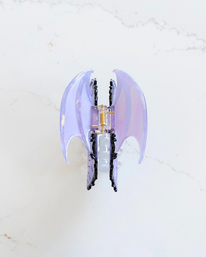Marbled wings of a dragon hair clip for fantasy readers featuring an array of purples on a white marble background.