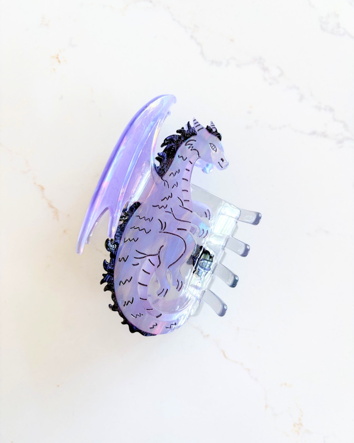 Purple dragon hair claw clip for fantasy fans on a white marble background.