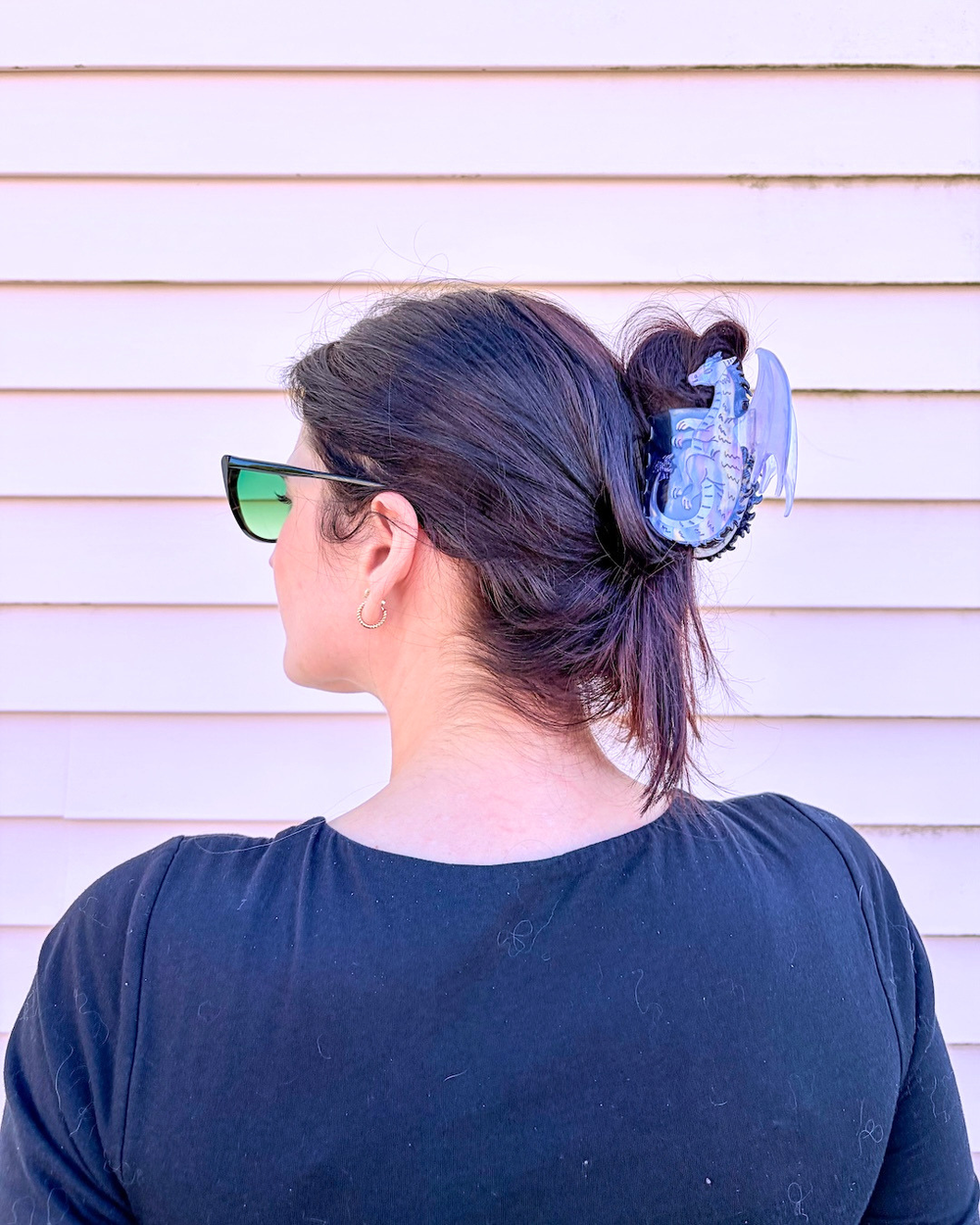 Woman wearing a purple, small dragon hair clip or fantasy fans against a pinkish background.