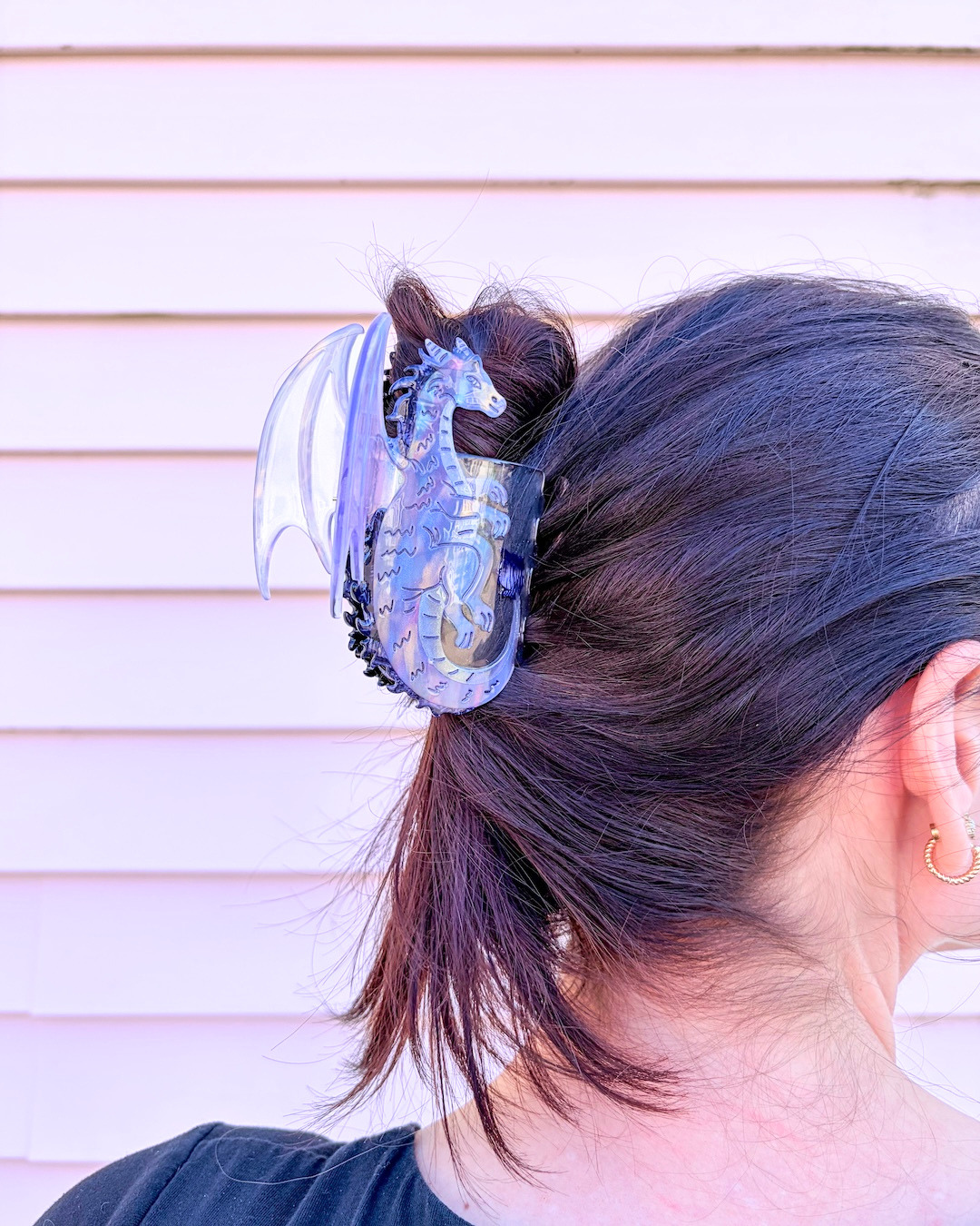 Close up of the dragon claw clip holding up dark hair, featuring an iridescent purple shine to the dragon.