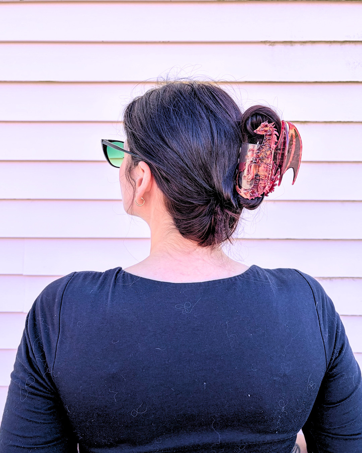 Woman wearing a red, small dragon hair clip or fantasy fans against a pinkish background.
