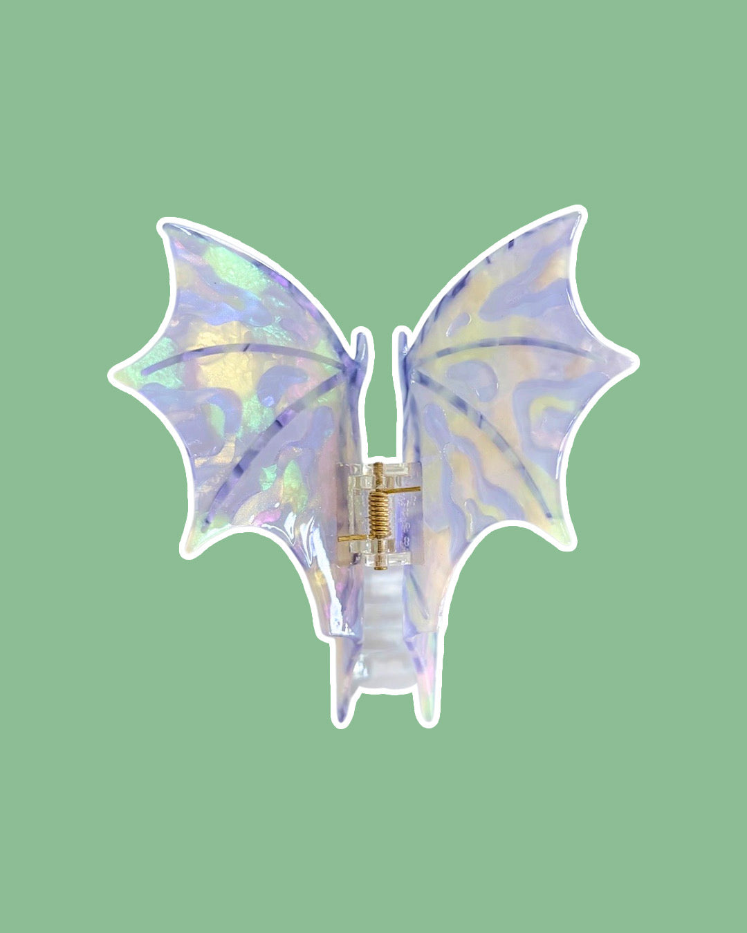 Purple, iridescent dragon wing hair clip against a green background.
