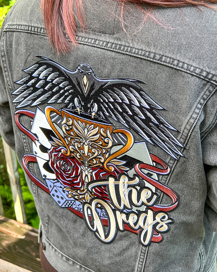 Iron-on patch for Six of Crows fans featuring a design with classic hallmarks of the crows including a crow, dice, and playing cards with &