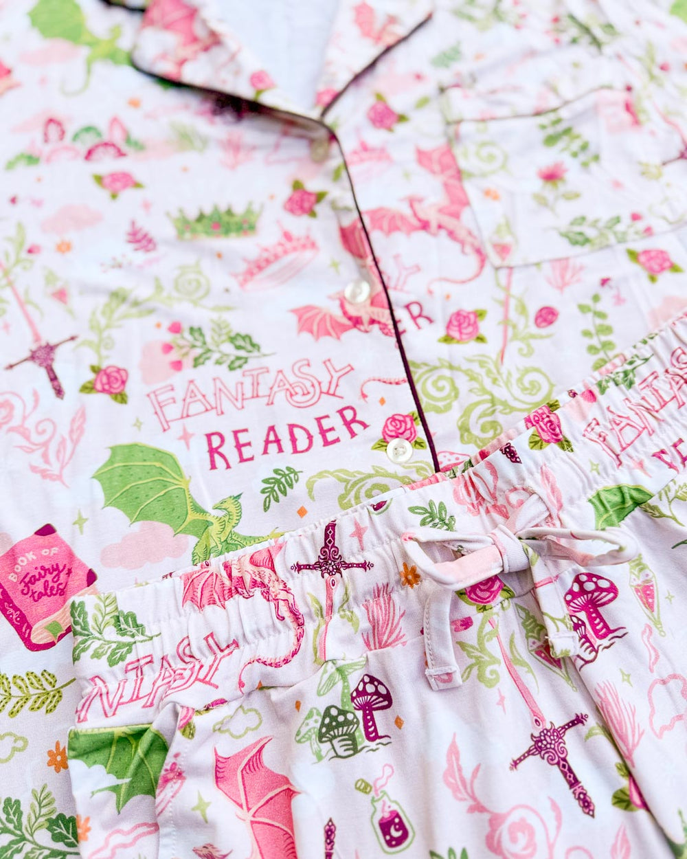 Close up of the fantasy reader pajamas set featuring dragons, a book of fairy tales, potions, mushrooms, swords, and more.