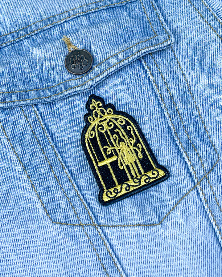 Patch for Plated Prisoner fans featuring a gold and black gilded cage design.