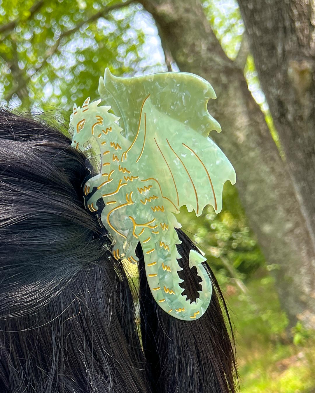 Hair clipped half-up-half-down with a green and gold detailed bookish hair clip for fantasy readers in the shape of a dragon.