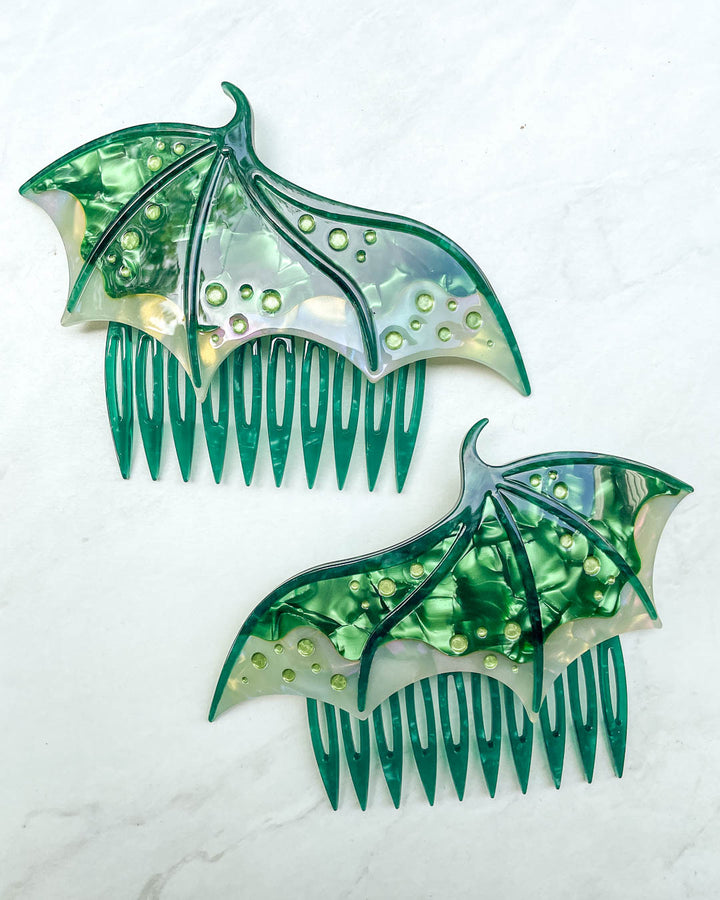 Hair combs for fantasy fans featuring two green combs in the shape of dragon wings with engraved embellishments and a pearlescent green color.