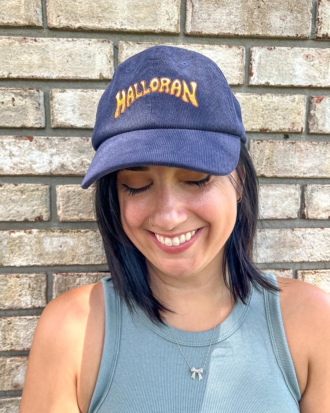 Person wearing the If Not For My Baby hat for Kate Golden fans featuring a yellow bubble letter logo for Halloran on navy blue corduroy.