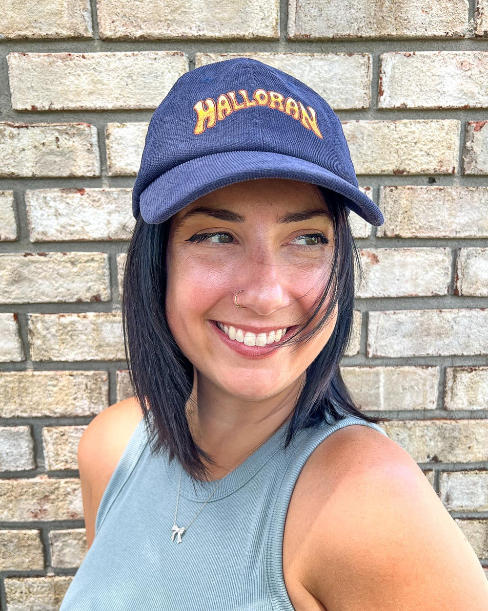 Navy blue Kate Golden cap featuring a yellow logo for Halloran from If Not For My Baby.