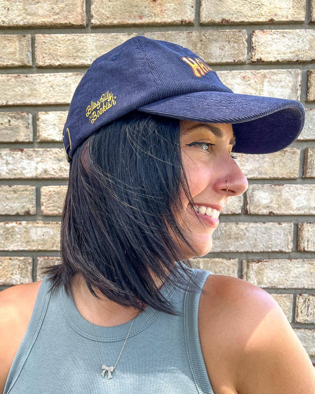 Side of the navy blue Halloran hat for If Not For My Baby fans featuring the Blissfully Bookish logo in yellow