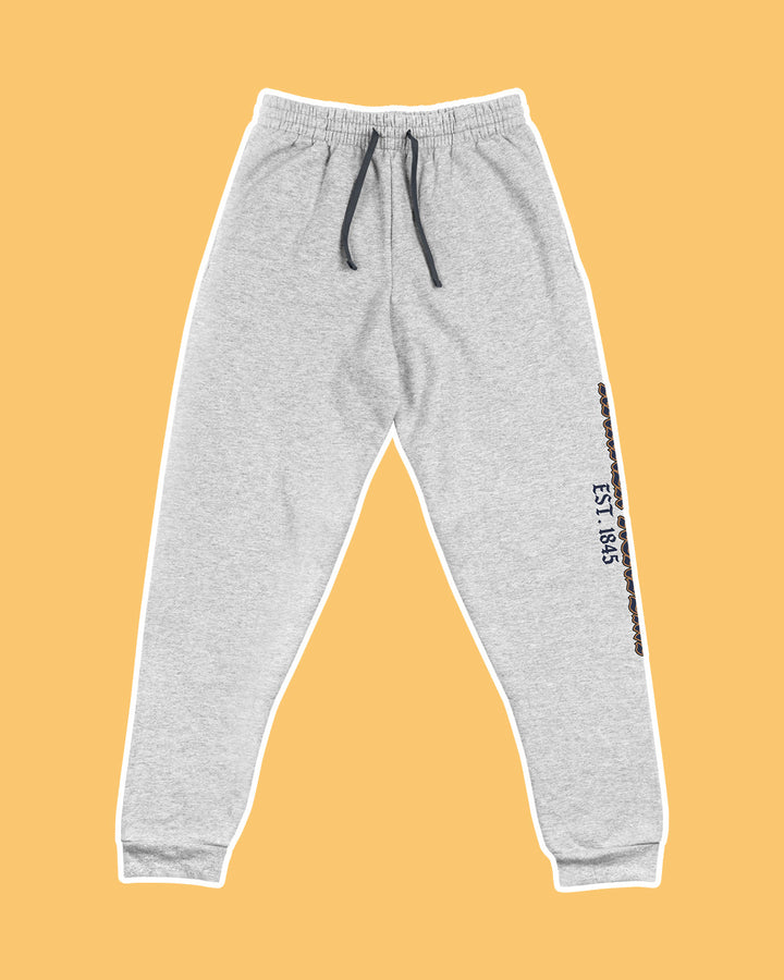 Gray sweatpants on a light orange background with "Harker Academy, EST. 1845" down the left pant leg.
