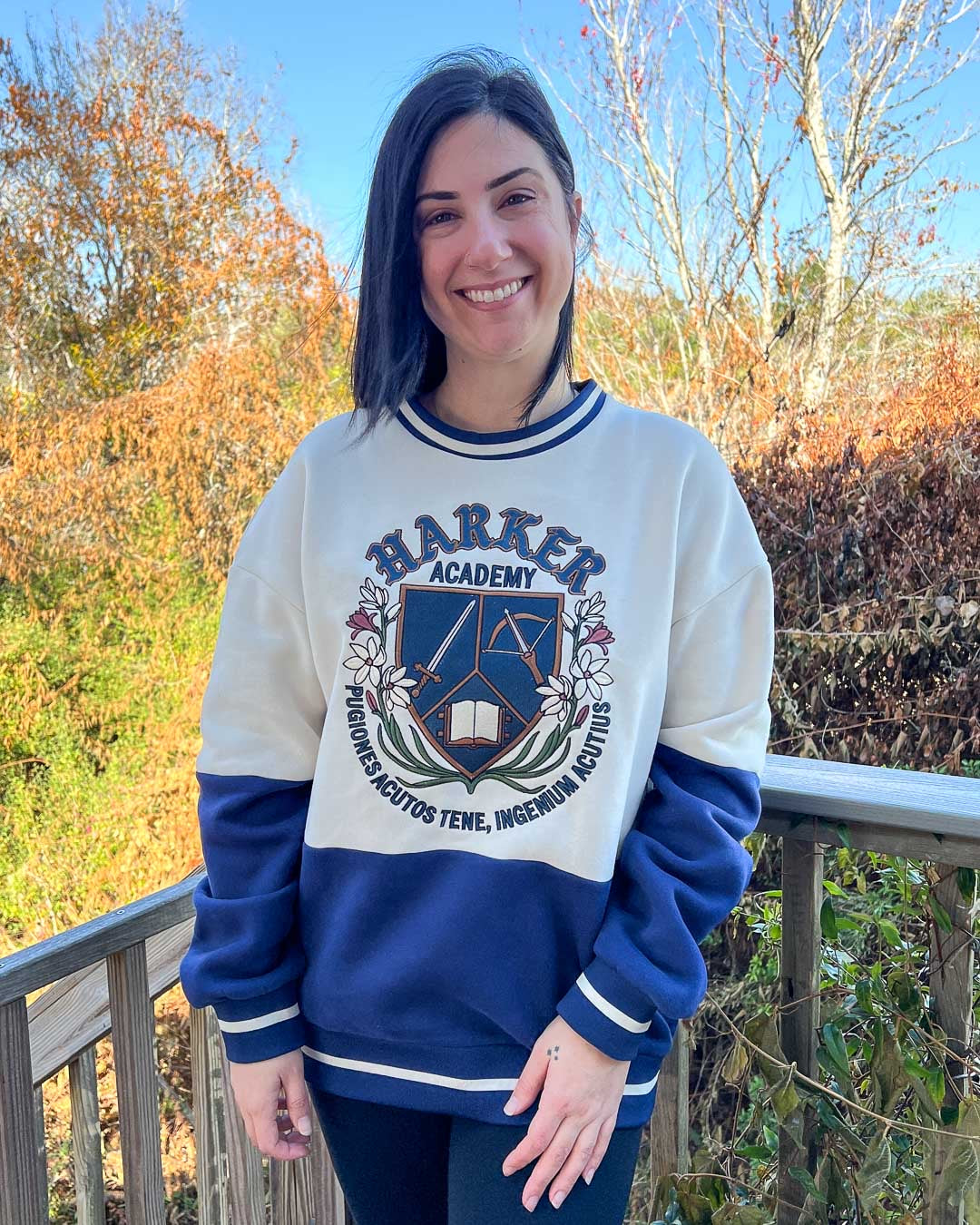 Dual-tone sweatshirt with blue on the bottom and white on the top with stripped details around the collar and bottom featuring a logo for Harker Academy from Half City by Kate Golden.