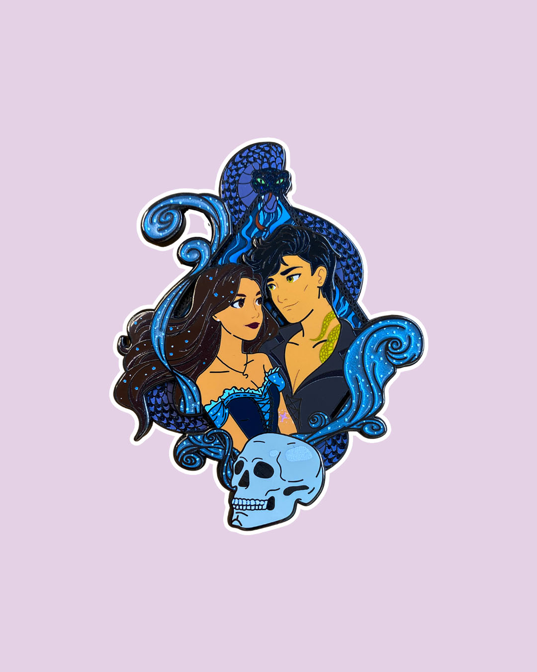 Kingdom of the Wicked enamel pin featuring Emilia and Wrath with a skull in front of them and a blue snake poised above them.
