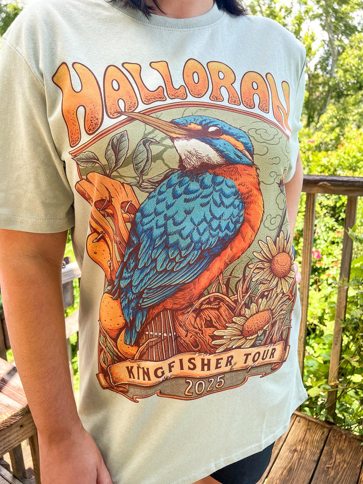 Light green Kate Golden t-shirt featuring a kingfisher perched on a guitar surrounded by wildlife with the text &