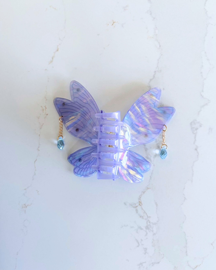 Bottom view of the fantasy fairy wing claw clip for book lovers featuring an iridescent shine to the purple and dangling gems off the sides of the wings.