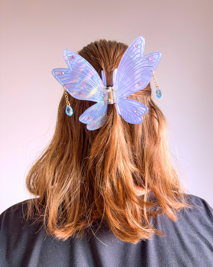 Woman wearing a fairy hair clip for fantasy readers featuring an iridescent purple color and dangling gems.