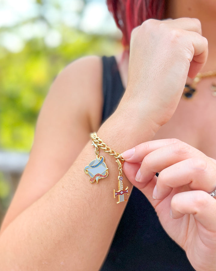 Legendborn charms modeled on a wrist featuring the Legendborn symbol and Excalibur.