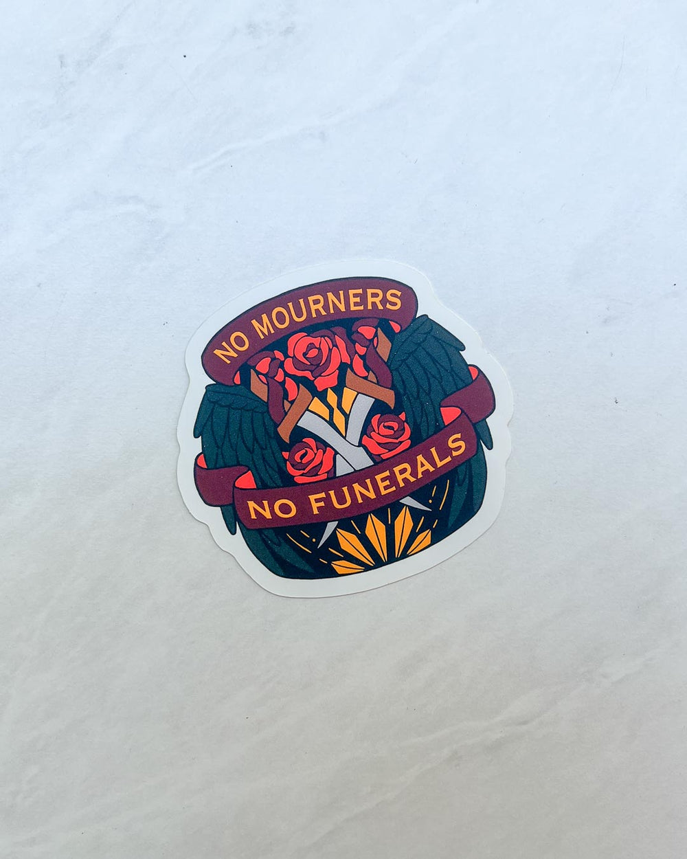 No Mourners No Funerals sticker for Six of Crows fans featuring an illustrated design of swings, roses, and crossed swords.