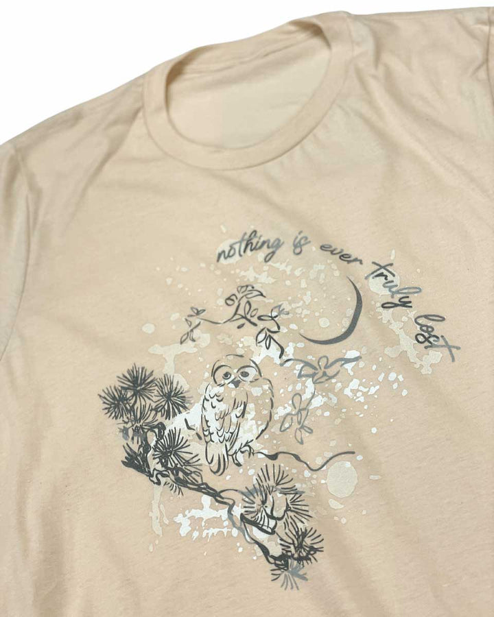 Close up of the Wild is the Witch shirt for Rachel Griffin fans featuring an illustrated design of an owl perched on a branch under a crescent moon with the quote ‘nothing is ever truly lost.’