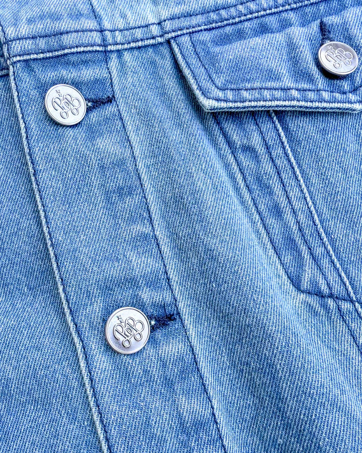 Close up of the buttons on the soft as petals jean jacket, featuring the Blissfully Bookish logo on each one.