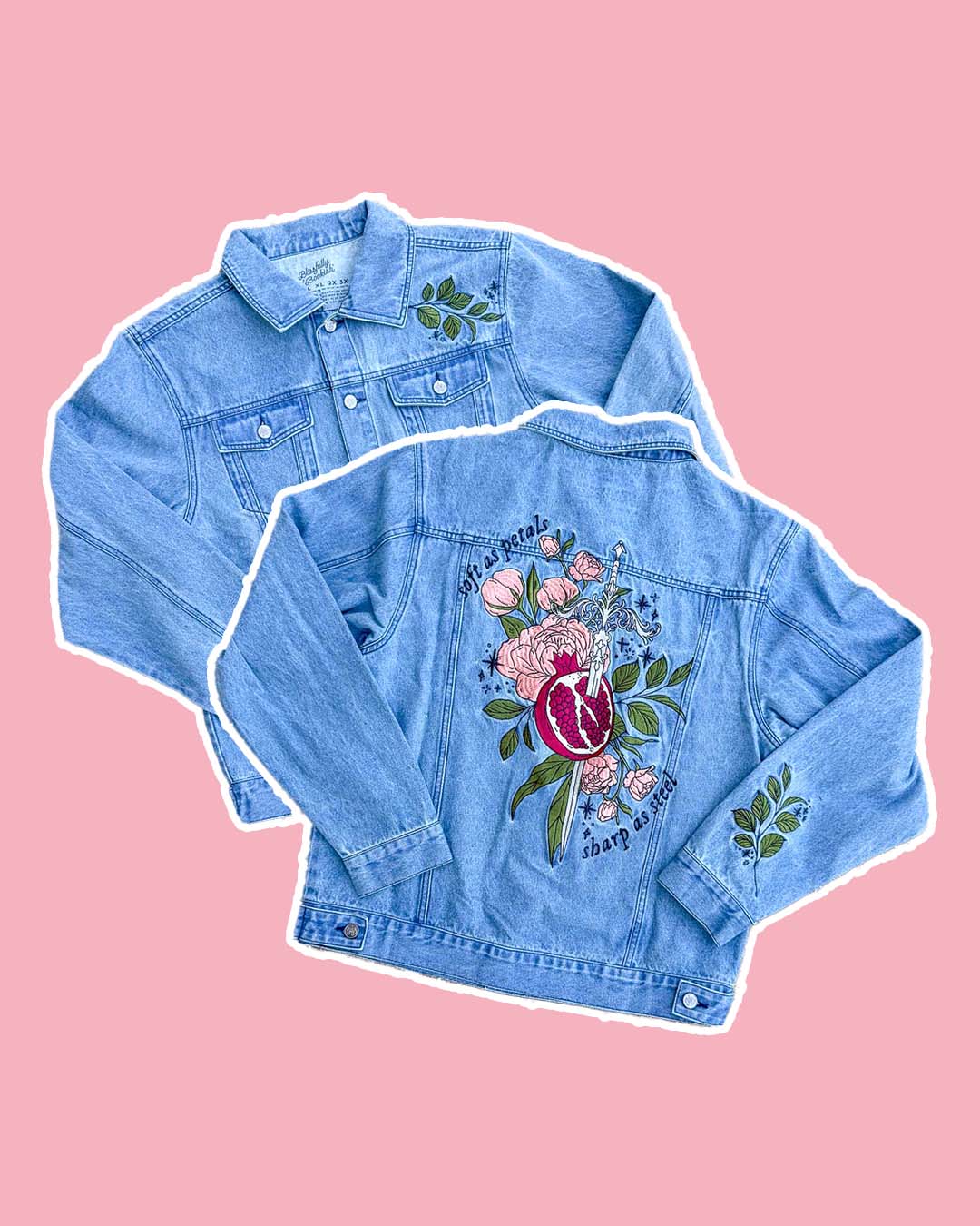 Soft as petals denim jacket featuring embroidered elements of a sword spearing a pomegranate surrounded by flowers and greenery with the quote &