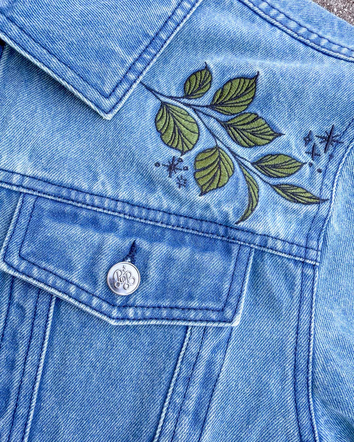 Close up of the shoulder design on the soft as petals jacket, featuring embroidered leaves and stars.