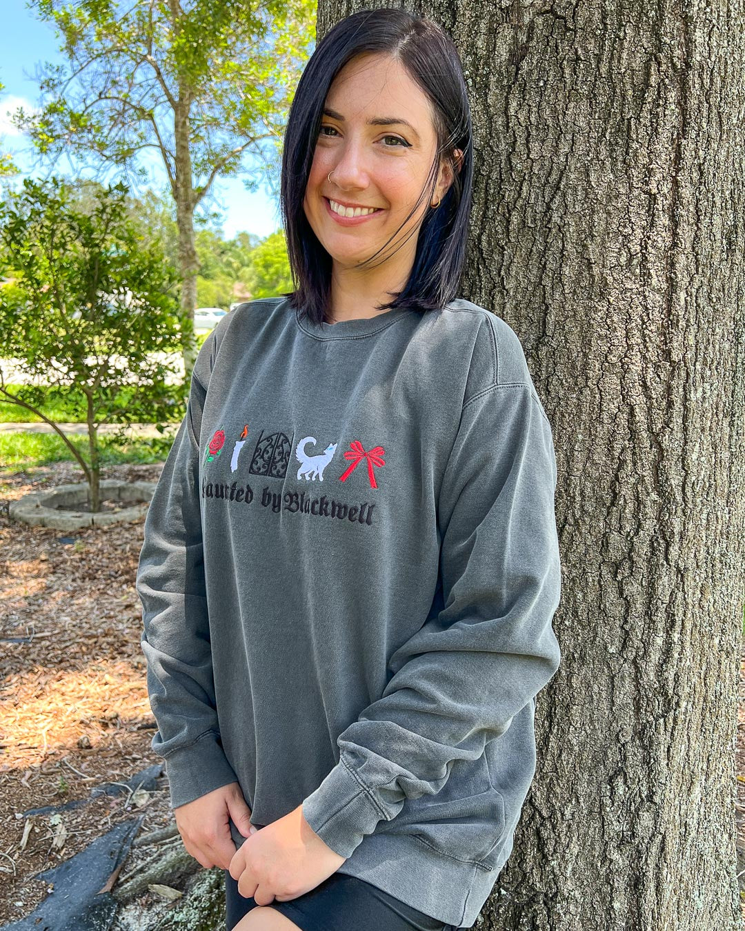 Woman wearing a gray embroidered sweatshirt inspired by Phantasma by Kaylie Smith with the phrase &