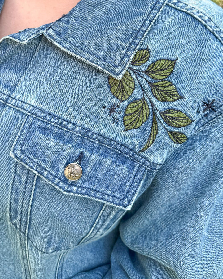 Embroidered fantasy apparel for book lovers featuring a close up of the shoulder embroidered leaves detail.