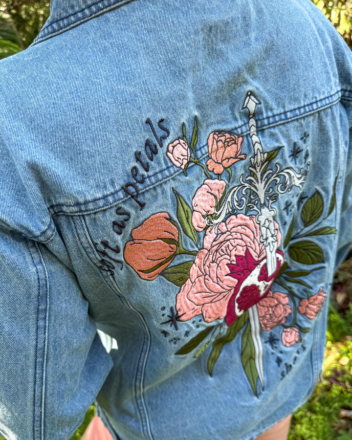Embroidered fantasy denim jacket with an embroidered sword, pomegranate, roses, leaves, stars, and the quote &