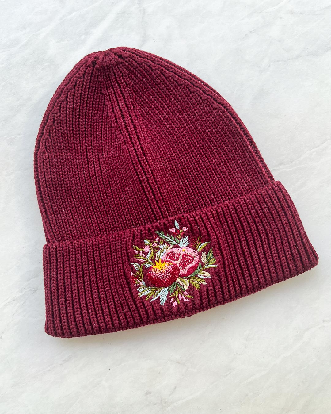 Embroidered beanie for Hades and Persephone lovers with a pomegranate embroidered on the front surrounded by greenery.