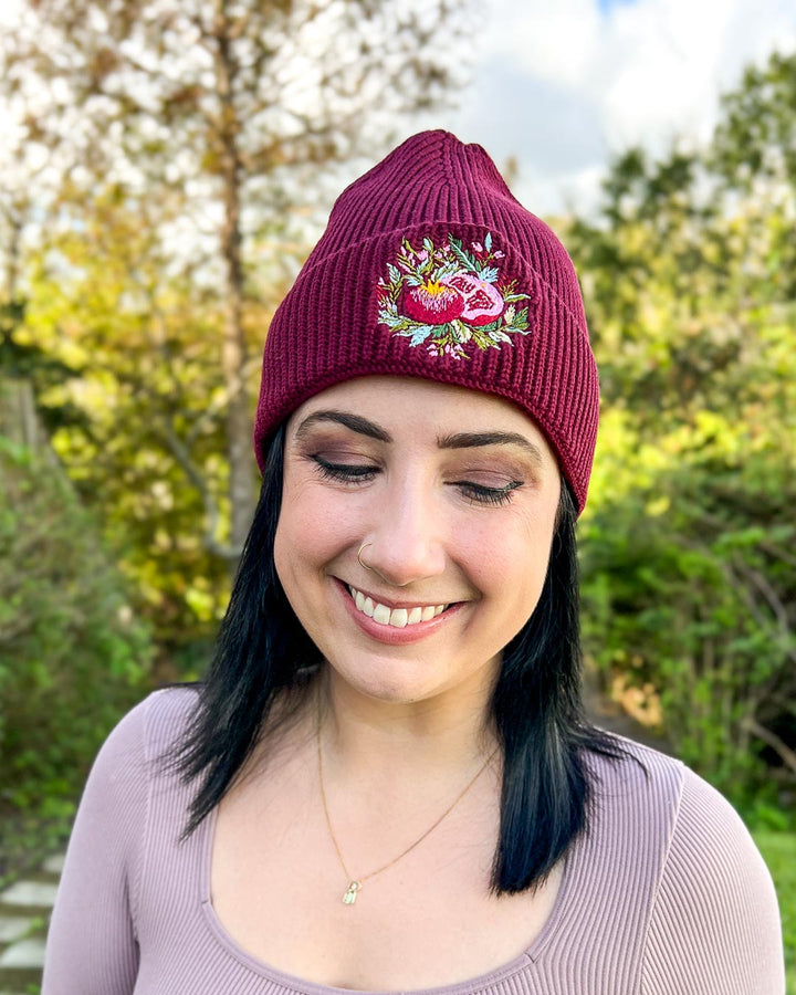 Fantasy hat for Hades and Persephone fans with an embroidered pomegranate on a rib knit beanie.
