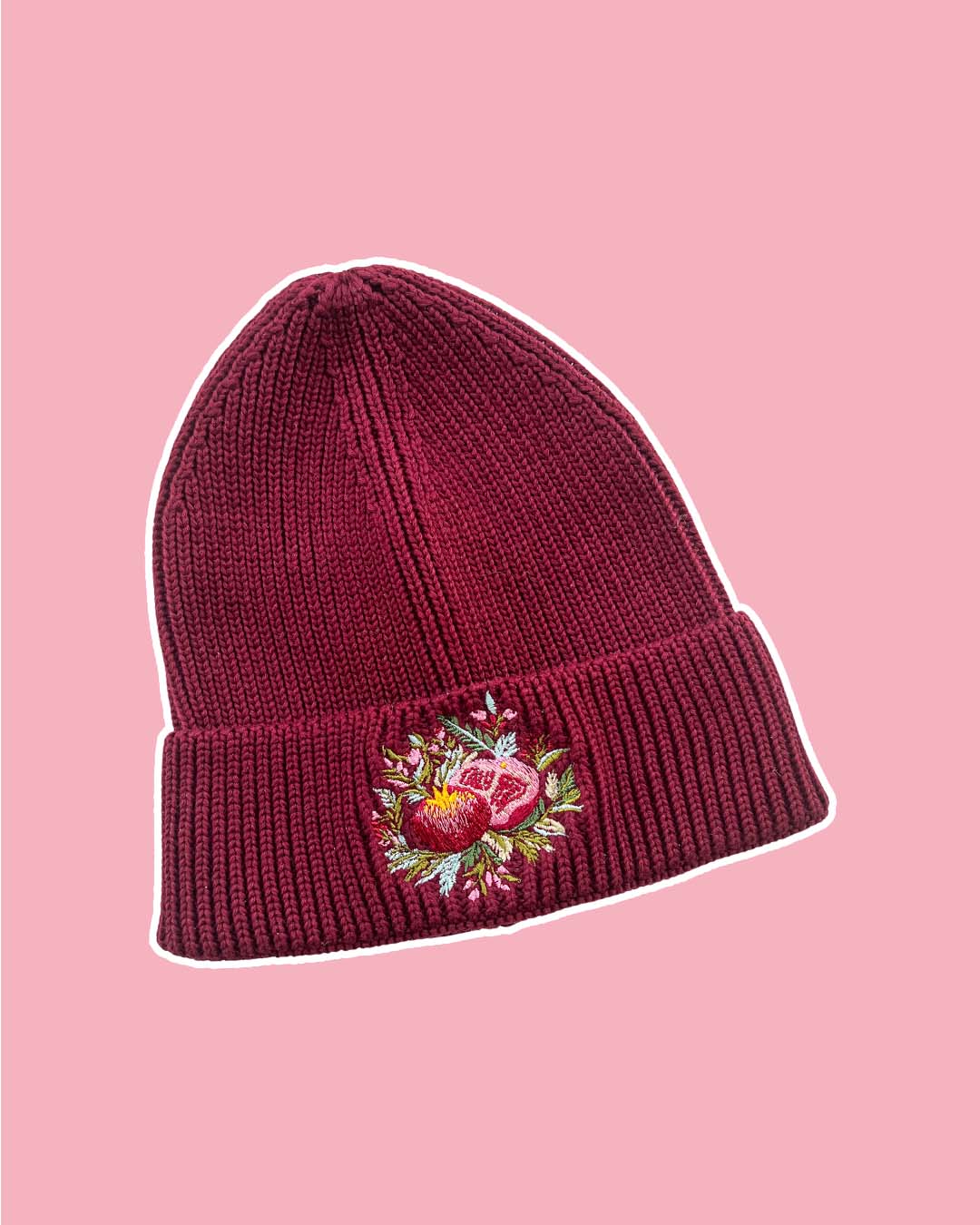 Red rib knit fantasy beanie with embroidered pomegranate surrounded by flowers on the front.