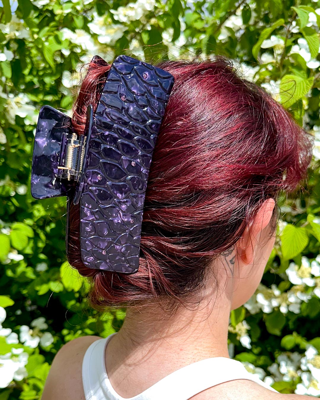 A dual-tone purple bookish hair clip for fantasy lovers featuring subtle dragon scales with pearlescent designs and dark purple gems.